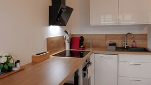A modern kitchen with a built-in oven, a coffee machine, a sink, and wooden cabinetry. - Panoramik station +parking (Nancy)