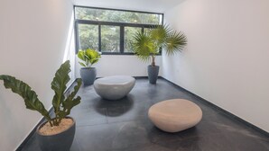 Et moderne interiør med et stort vindue, en ventilator i loftet og tre plantede planter.