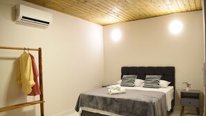 Ein Schlafzimmer mit Bett, Nachttischen, einer Kleiderstange und einer Klimaanlage.