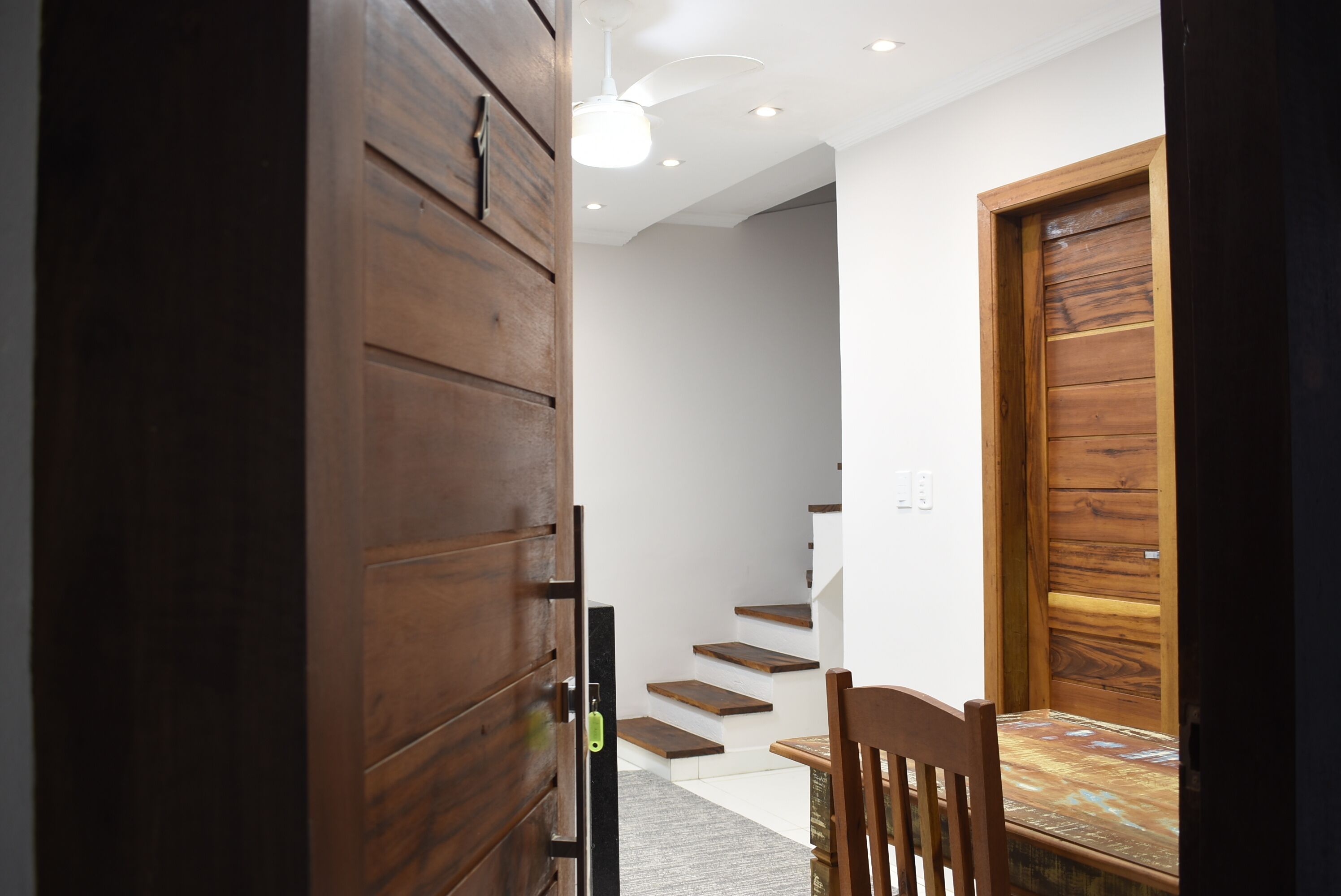 A wooden door, a staircase, a chair, and a ceiling fan.