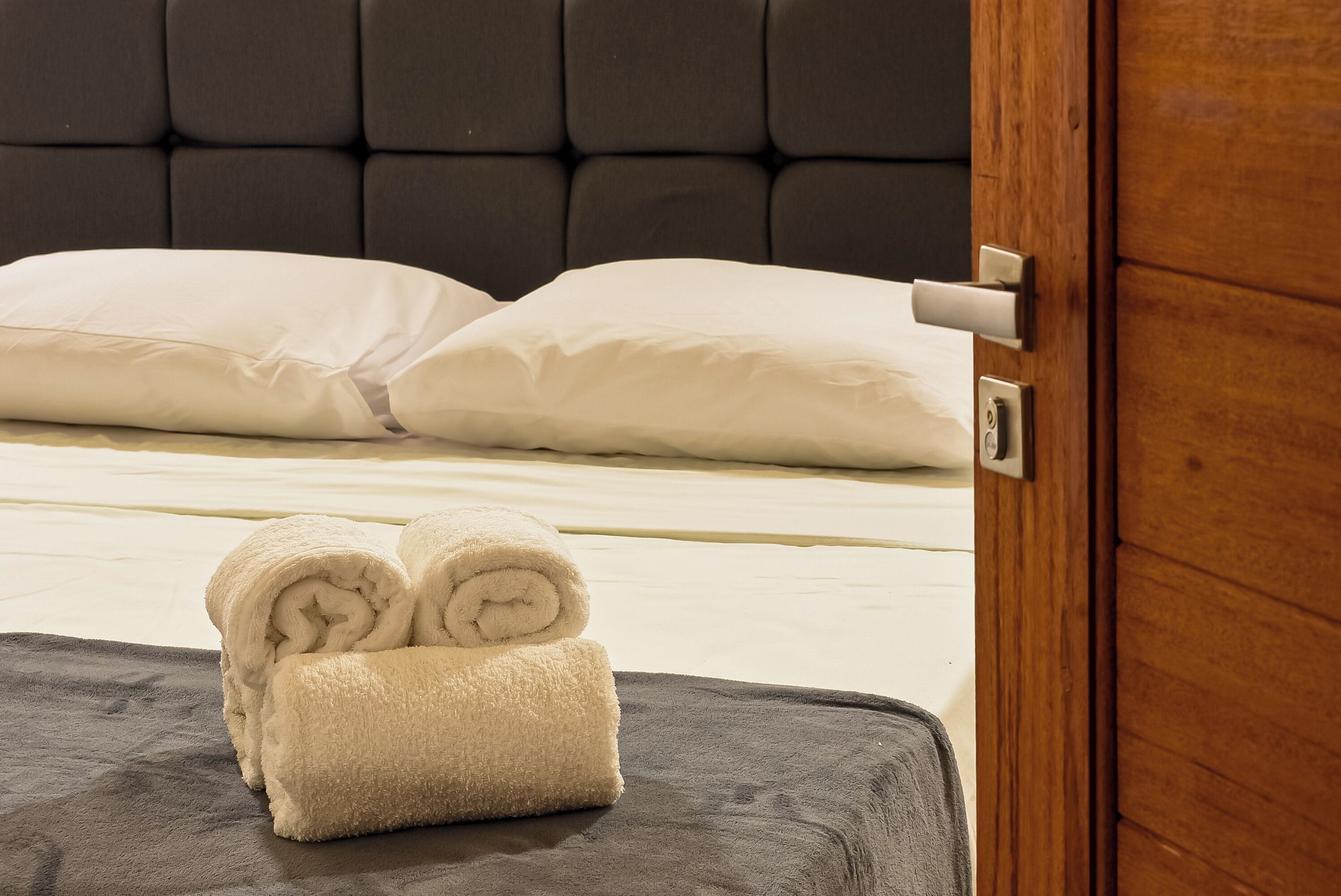 Una habitación de hotel con una cama, una puerta de madera y una toalla sobre la cama.