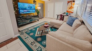 Ein Wohnzimmer mit Sofa, Couchtisch, Fernseher und einem gemusterten Teppich.