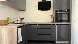 A modern kitchen with a built-in oven, a microwave, and a black wall-mounted TV.