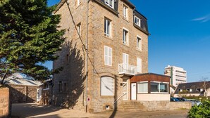 A stone building with multiple windows, a balcony, and a garage. - Renovated apartment with sea view - Trébeurden (Trébeurden)