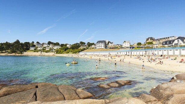 A coastal beach with clear water, people in the water, and buildings in the background. - Renovated apartment with sea view - Trébeurden (Trébeurden)