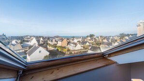 A view through a skylight of a residential area with houses and a distant coastline. - Renovated apartment with sea view - Trébeurden (Trébeurden)