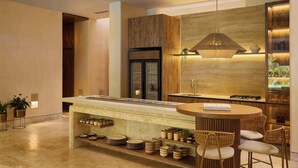 Una cuina moderna amb una illa central, electrodomèstics integrats i una paret decorativa de fusta.