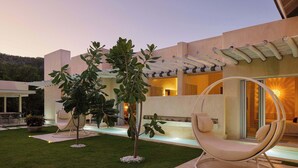 Zona exterior moderna amb una cadira penjant, un arbre petit i un jardí ben cuidat.
