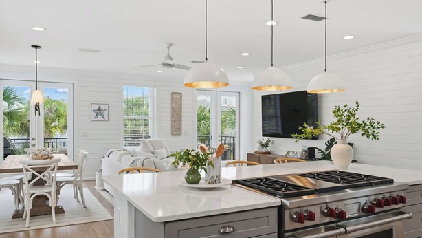 Una cocina moderna con una isla central, electrodomésticos de acero inoxidable, iluminación colgante y vistas al exterior.