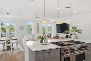 A modern kitchen with a central island, stainless steel appliances, pendant lighting, and a view of the outdoors. - Splash Pad- Dog Friendly- Seacrest Beach! (Rosemary Beach)