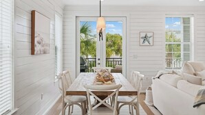 Un comedor con una mesa, sillas, una lámpara colgante y vistas al exterior.