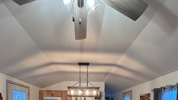 A spacious kitchen with a central island, wooden cabinets, and a ceiling fan.