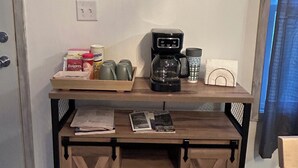 A small kitchenette with a coffee maker, mugs, and a tray of Folgers coffee.