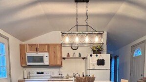 A kitchen with wooden cabinets, a microwave, a stove, a refrigerator, and a chandelier.