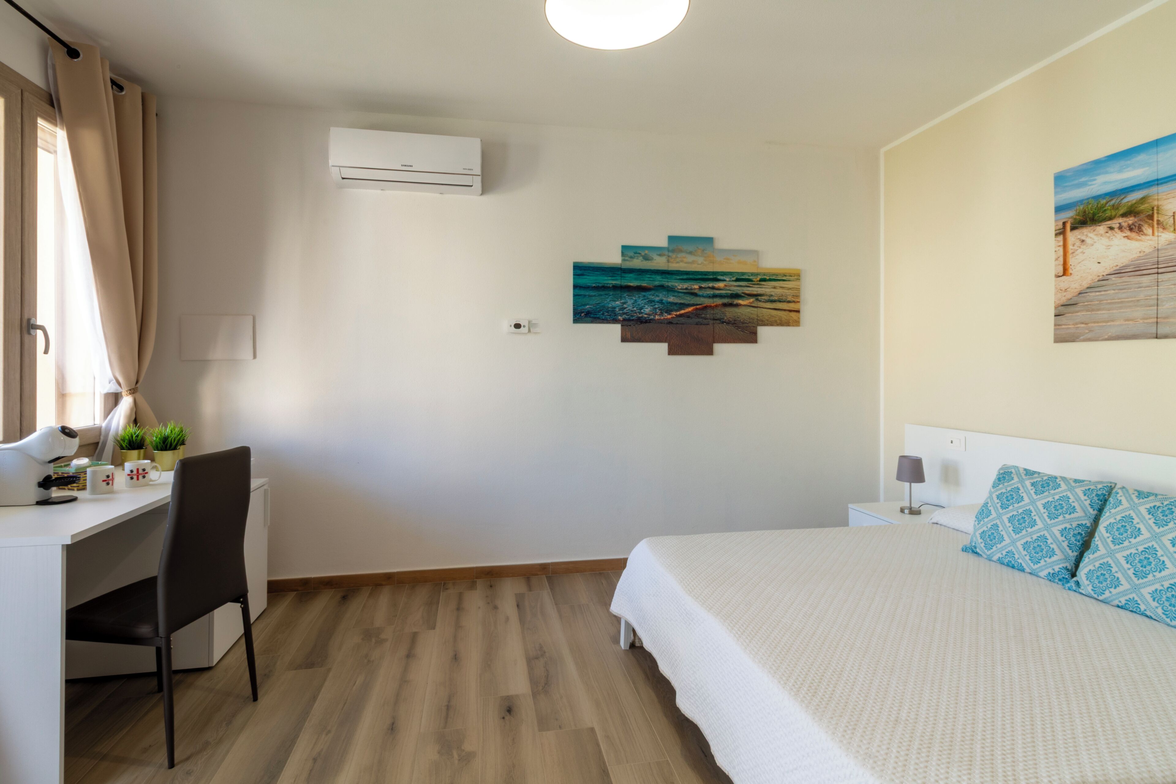 Une chambre à coucher avec un lit, un bureau, une chaise et une œuvre d’art accrochée au mur.