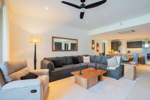 Een moderne woonkamer met een bank, fauteuils, een salontafel en een eethoek.