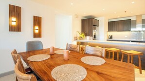 A modern kitchen with dark cabinets, a stainless steel refrigerator, and a built-in oven. - The Pearl Jaco Beach (Jacó)