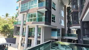 A multi-story building with balconies, large windows, and a glass railing. - Room-city Condo Phuket Walk to Central (Wichit)