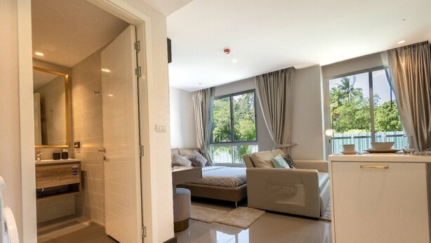 A modern hotel room with a bed, a sofa, a dining area, and a bathroom. - Room-city Condo Phuket Walk to Central (Wichit)