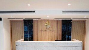 A reception desk with a marble top, a wooden panel with 'The City Phuket' logo, and air conditioning vents on the walls. - Room-city Condo Phuket Walk to Central (Wichit)