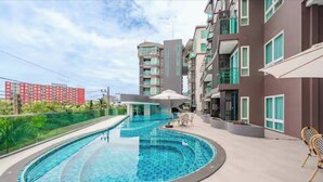 A modern residential building with a swimming pool, outdoor seating, and a view of neighboring buildings. - Room-city Condo Phuket Walk to Central (Wichit)