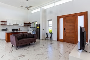 A modern kitchen with white cabinets, a marble floor, a sofa, and a TV. - Private Sosua Villa, Pool, Bbq, Sosua Ocean Village (Sosúa)