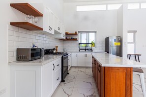 A modern kitchen with white cabinets, a marble floor, wooden shelves, a built-in oven, and a refrigerator. - Private Sosua Villa, Pool, Bbq, Sosua Ocean Village (Sosúa)