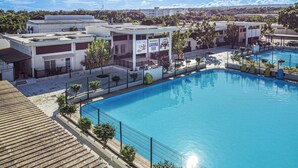 A swimming pool with a fenced area, a covered seating area, and buildings in the background. - Apartamentos en Parque Acuático (Sosúa)
