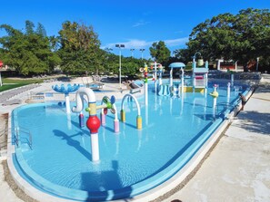 Ein Wasserpark mit Schwimmbecken, Rutschen und Spielgeräten.