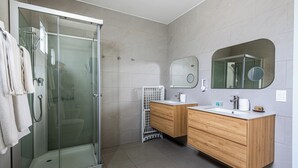 A modern bathroom with a glass-enclosed shower, wooden vanity, and a large mirror. - Apartamentos en Parque Acuático (Sosúa)