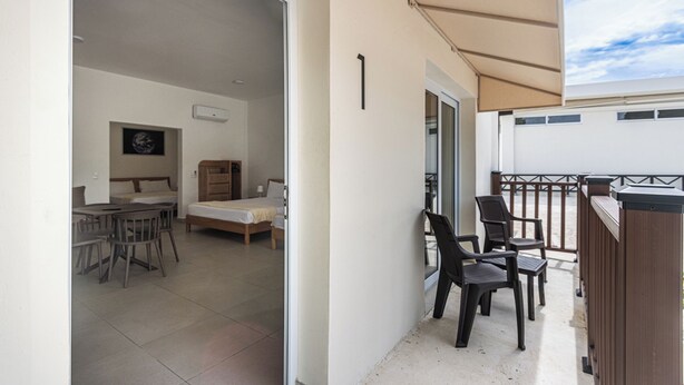 A balcony with chairs, a table, and a bed in the background. - Apartamentos en Parque Acuático (Sosúa)