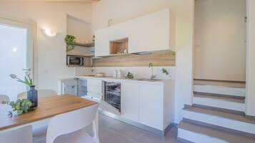 Una cocina moderna con armarios blancos, encimera de madera y lavavajillas empotrado.