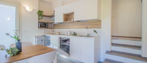 A modern kitchen with white cabinetry, a wooden countertop, and a built-in dishwasher.