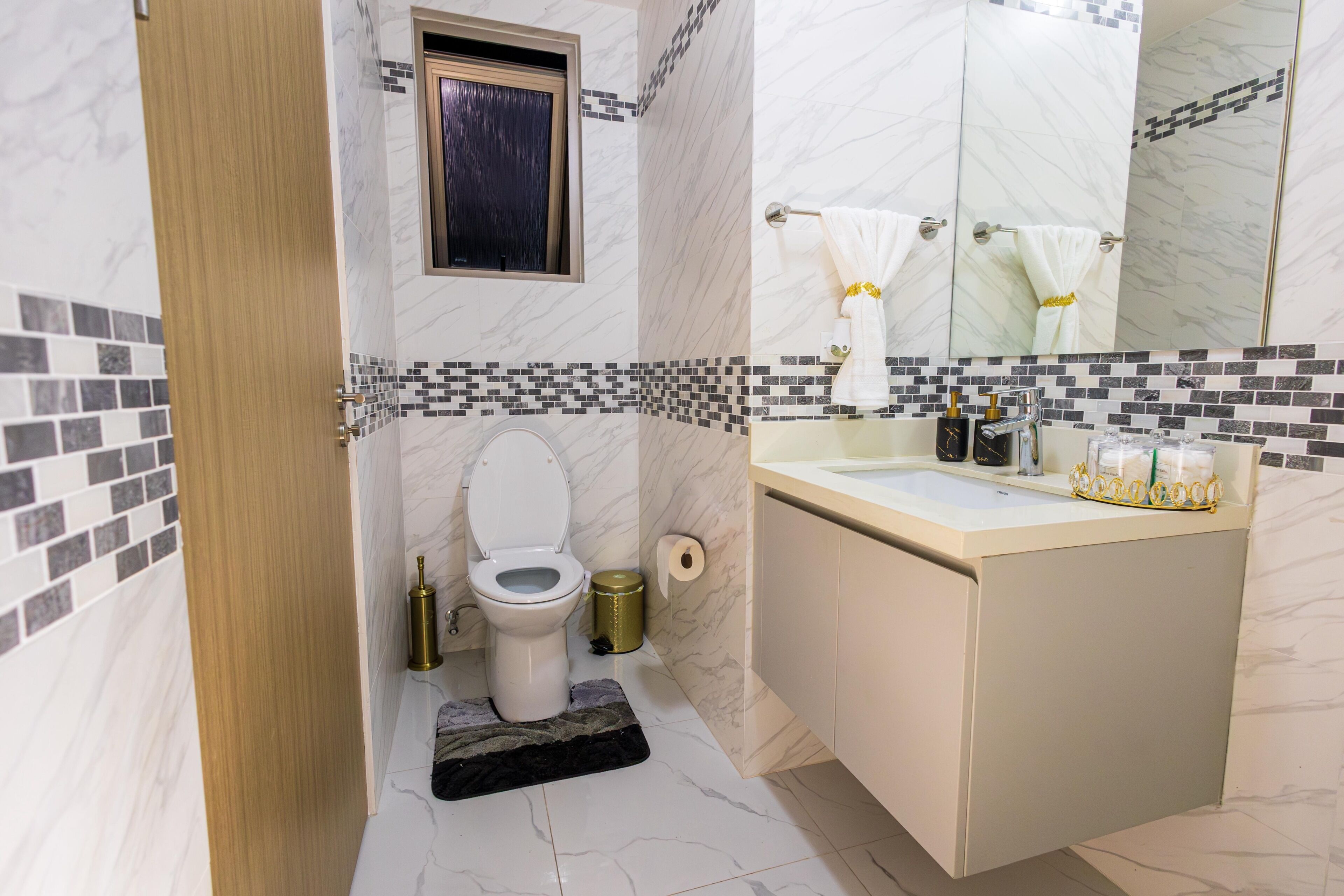 Een badkamer met toilet, wastafel, spiegel en een klein raam.