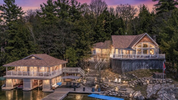 A waterfront property with a dock, a house with a balcony, and a staircase leading to a second level. - 6 bed 4 bath cottage on Lake Joseph (Port Carling)