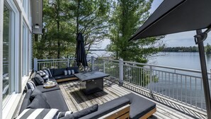 A deck with outdoor seating, a grill, and a view of a lake. - 6 bed 4 bath cottage on Lake Joseph (Port Carling)