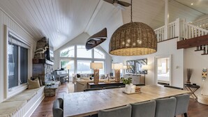 A spacious living area with a large wooden table, comfortable seating, and a high ceiling with exposed beams. - 6 bed 4 bath cottage on Lake Joseph (Port Carling)