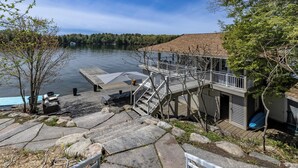 A lakeside property with a dock, outdoor seating, and a staircase leading to a deck. - 6 bed 4 bath cottage on Lake Joseph (Port Carling)