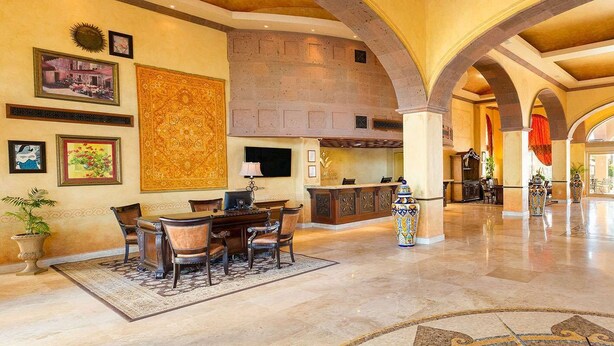 Un'ampia hall con zona pranzo, camino e un grande tappeto decorativo.