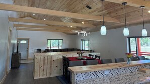 Eine geräumige Küche mit Holzbalken, einem Essbereich mit rotem Tischleinentuch und einer Bar mit einer Holzausstattung.