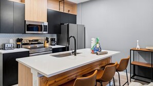 Una cocina moderna con una isla central, electrodomésticos negros y armarios de madera.