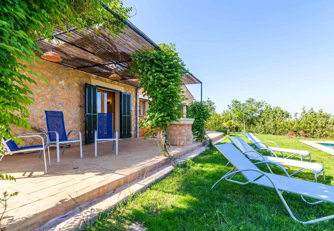 A stone building with a thatched roof, a covered patio, and a poolside area with lounge chairs.