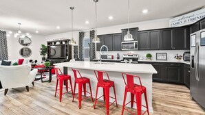 Een moderne keuken met een centraal eiland, barstoelen en een bord dat familie en vrienden welkom heet.