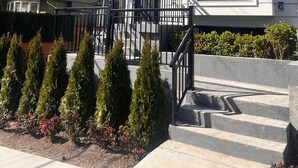 A two-story house with a balcony, a front door, and a staircase leading to the entrance. - Modern Spacious 2 Bed 2 Bath Townhouse (Vancouver)