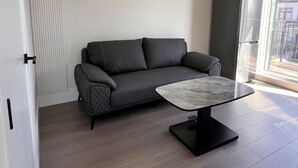A modern living room with a grey sofa, a marble coffee table, and a large window providing natural light. - Modern Spacious 2 Bed 2 Bath Townhouse (Vancouver)