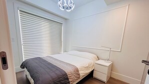 A bedroom with a bed, bedside table, and a wall-mounted light fixture. - Modern Spacious 2 Bed 2 Bath Townhouse (Vancouver)