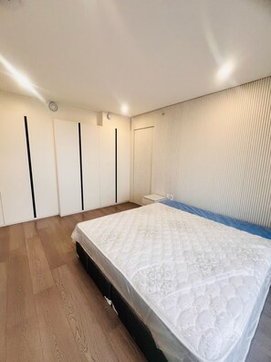 A bedroom with a bed, wooden flooring, a wardrobe with vertical handles, and a wall with a vertical panel design. - Big 3 bed+ 3 Bath townhome with rooftop views (Vancouver)