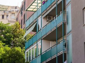 Ein mehrstöckiges Gebäude mit Balkonen, Klimaanlagen und Blick auf die umliegenden Gebäude.