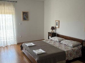 Ein Schlafzimmer mit einem Bett, einem Nachttisch, einer Lampe und zwei gerahmten Bildern an der Wand.