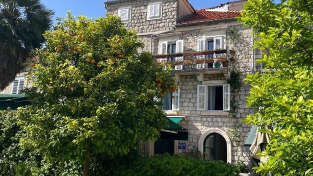 A stone building with a red-tiled roof, multiple balconies, and a green awning. - Ston Heritage Apartment with City view (Ston)